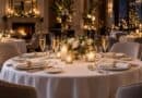 Candlelit hotel dining table set with champagne glasses, white roses and gold napkin rings