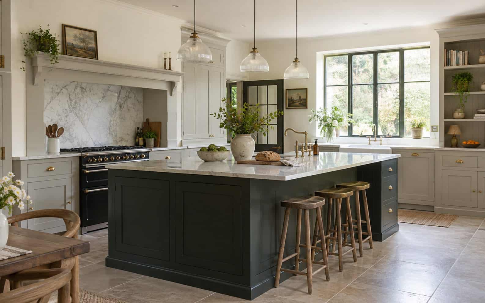 Shaker-style kitchen with a dark green island, marble worktop and wooden bar stools