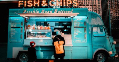 Turquoise vintage street food van selling fish and chips, with a customer in an orange backpack at the serving hatch