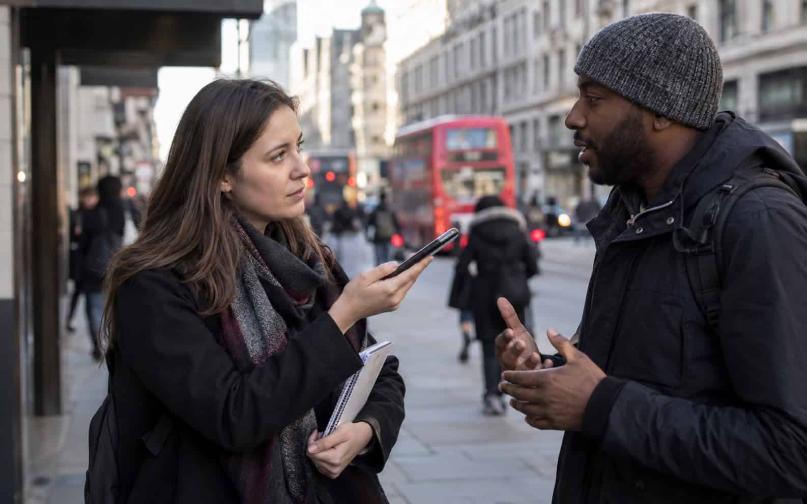 Reporter with a notebook recording a street interview on a phone